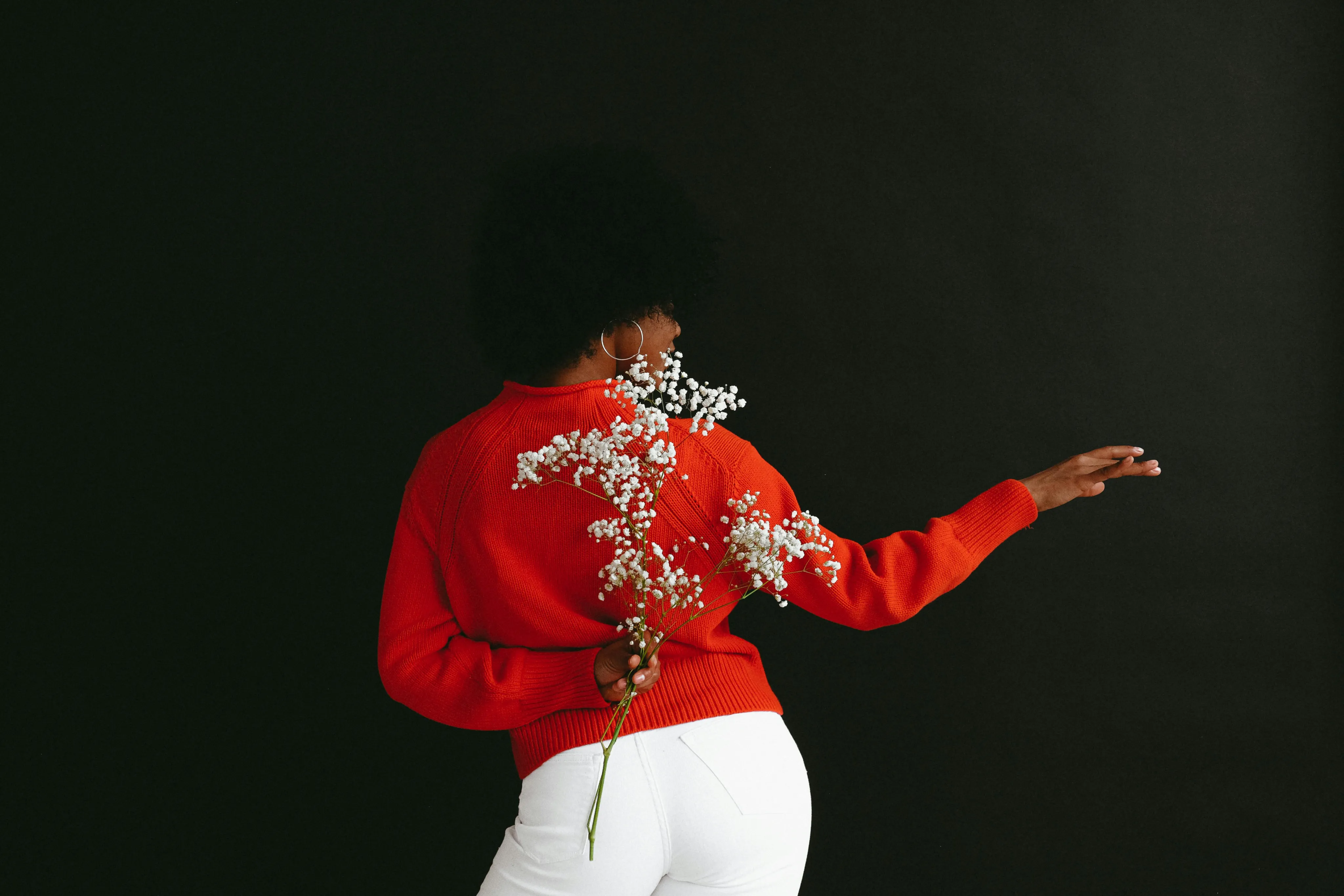 Model Posing with flowers for a photoshoot in red and white jean pants